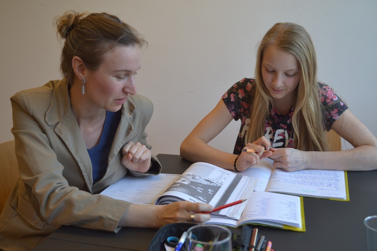 Frau hilft Schülerin bei Hausaufgaben © Caritas Lerncafé