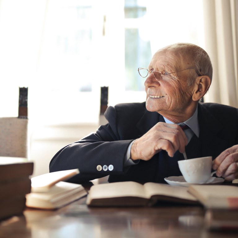 Älterer Mann mit Kaffee und Büchern © Andrea Piacquadio von Pexels